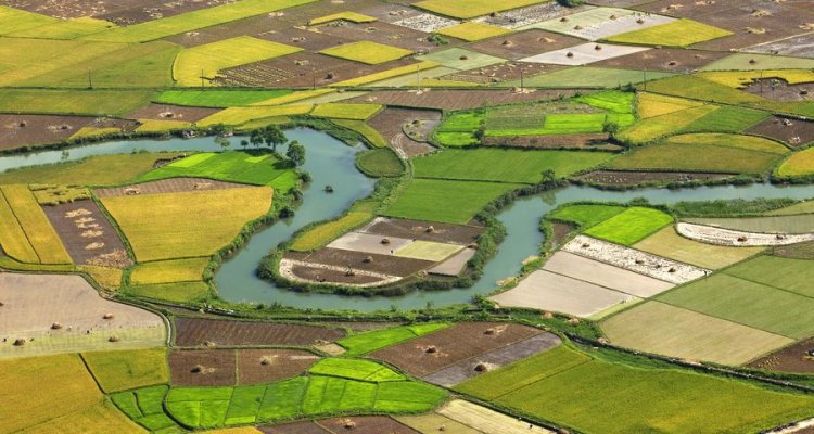 Een rivier stroomt door een lappendeken van landbouwgrond