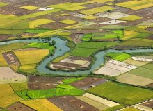 Een rivier stroomt door een lappendeken van landbouwgrond